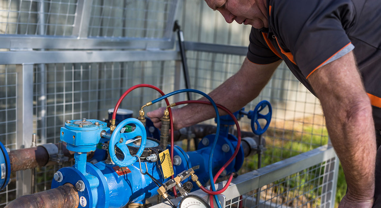 Technician performing certified backflow preventer inspection